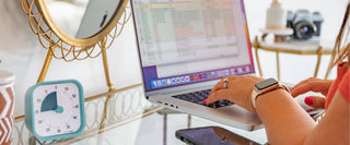 Person using a laptop with a clock and camera in the background