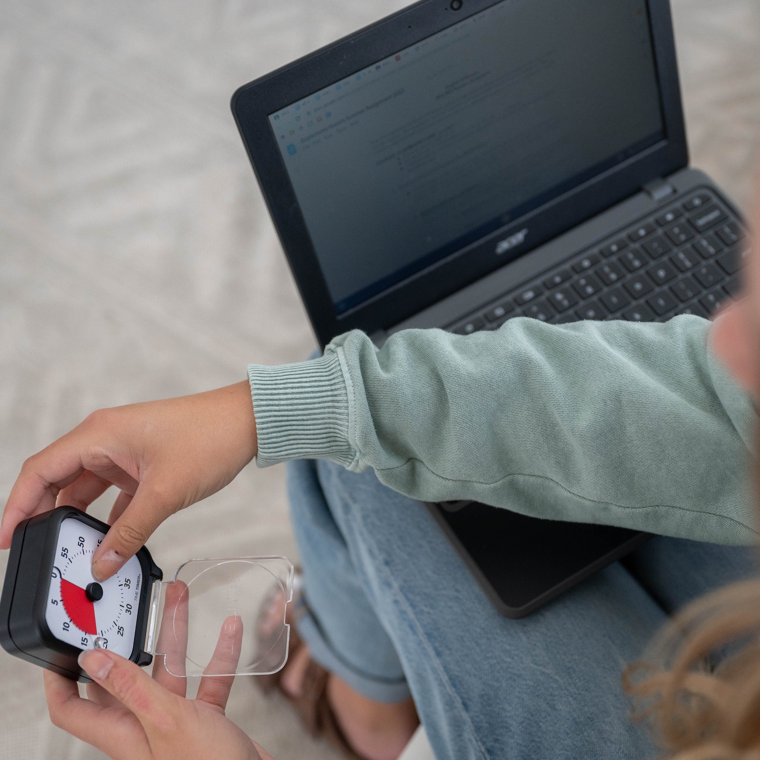 Person using a timer in front of a laptop on a bed