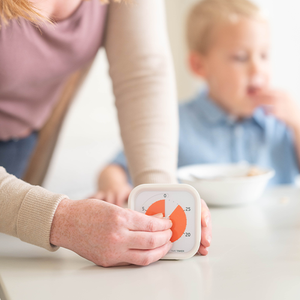 Person holding a digital timer with a child in the background