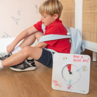 Child sitting on a chair with a motivational clock on the floor