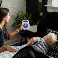 A mom is showing the Time Timer PLUS 120 minute visual timer to her child. The child is in bed, ready for a nap. The visual timer is set for 2 hours to indicate how long the child should nap. The mom shows the kid the purple disk to tell them when the purple is gone, it's time to get up from their nap.