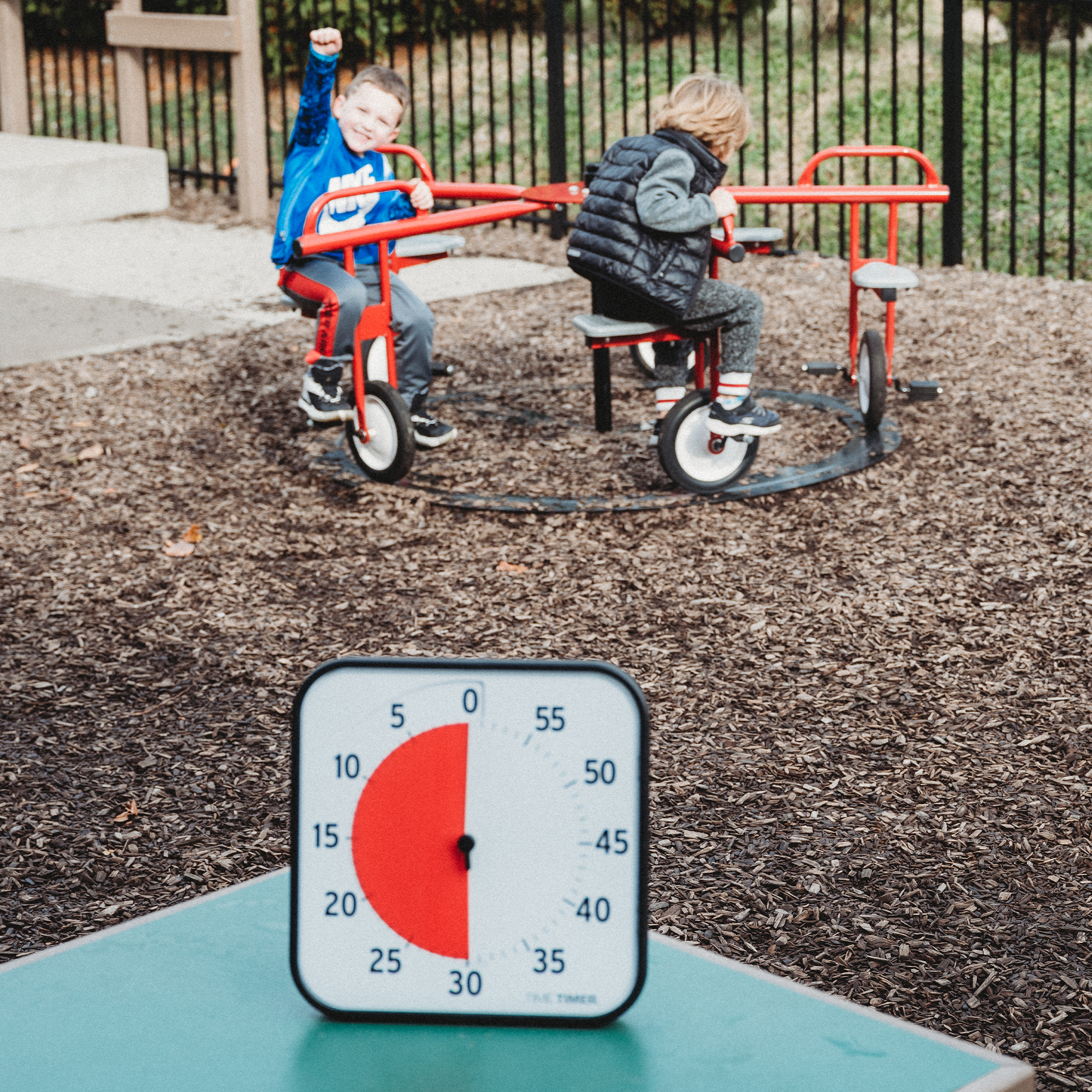 Two children playing on a red playground toy with a Time Timer visual timer in the foreground showing 30 more minutes of recess.