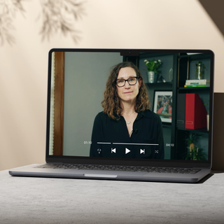 Laptop displaying a video call with a woman on a neutral background
