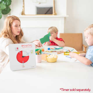 Woman and two children sitting at a table with educational materials, including a book about days of the week.