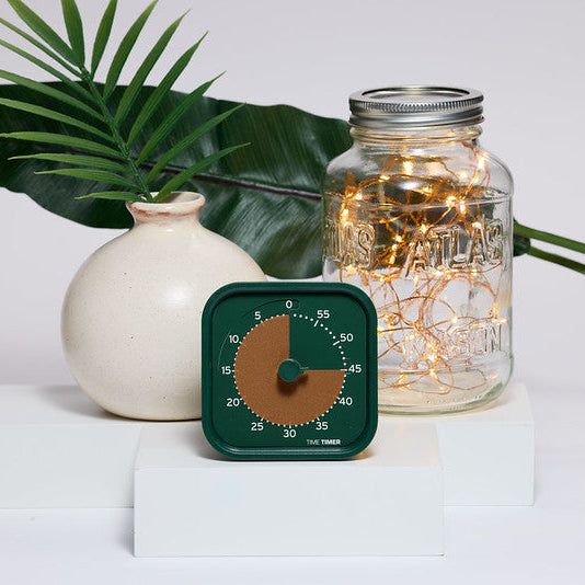 forest green timer with metallic orange disk in front of a decorated backdrop