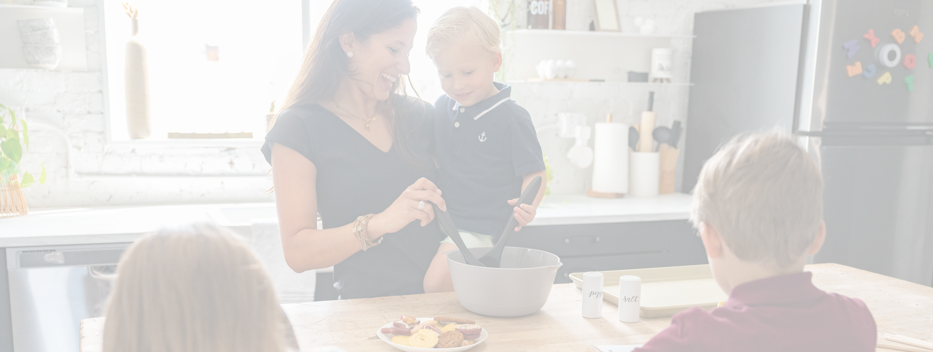 Two women and a child in a kitchen setting, with one woman stirring something in a bowl.