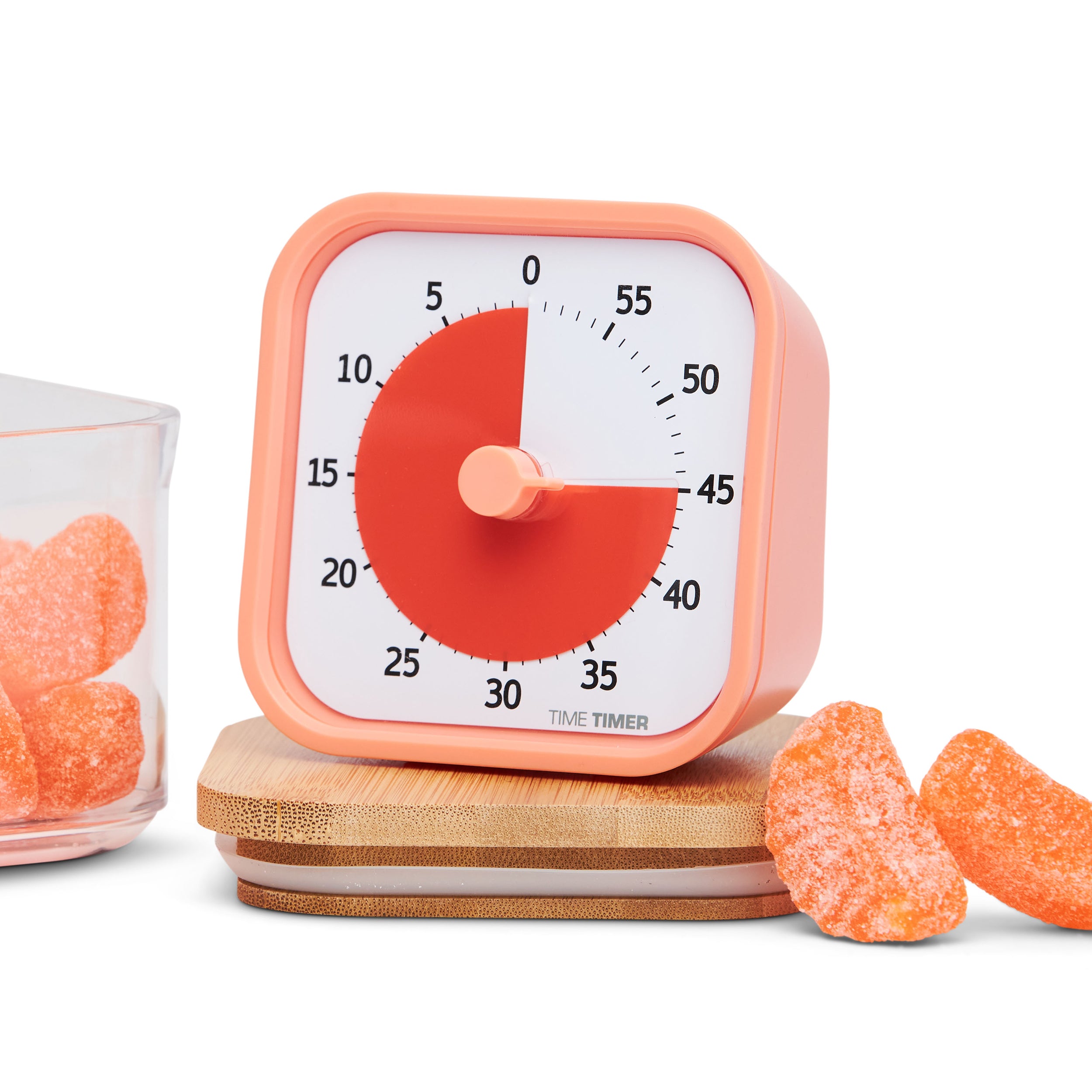 Time Timer MOD - Home Edition - visual timer. This collection of visual timers have colorful disks that disappear as time elapses. Pictured is the Dreamsicle Orange version. The outside of the timer is a sherbert colored orange while the inside is a more saturated bright orange. The timer is surrounded by orange slice candies.  