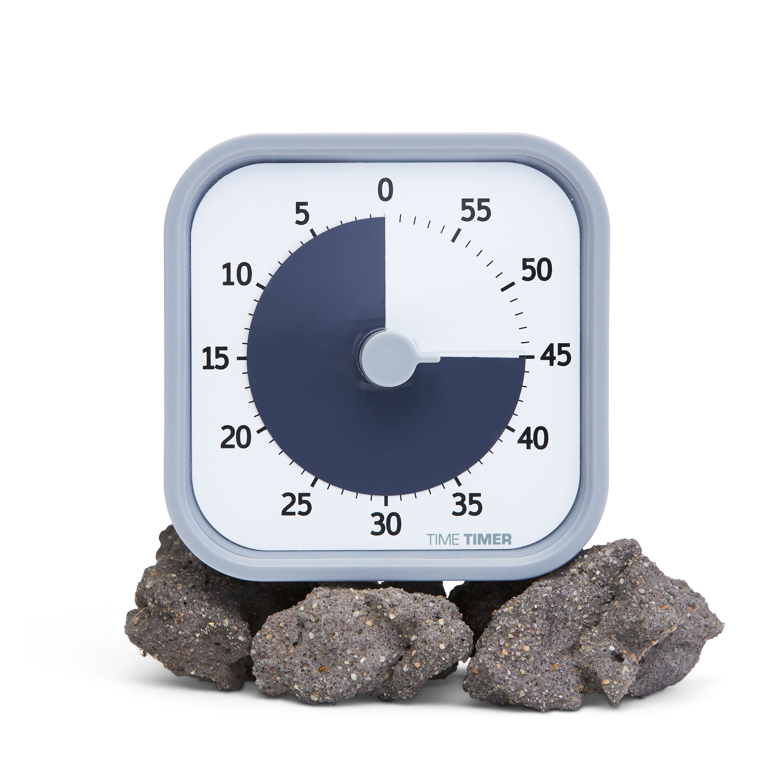 Time Timer MOD - Home Edition visual timer. This visual timer is part of a collection on trendy new colors. The timer shows a colored disk that disappears as time elapses. Pictured is the Pale Shale color, with a light grey-purple on the exterior of the timer and a dark grey-purple for the disk. Pictured with some natural rocks to show the calming nature of the timer. 